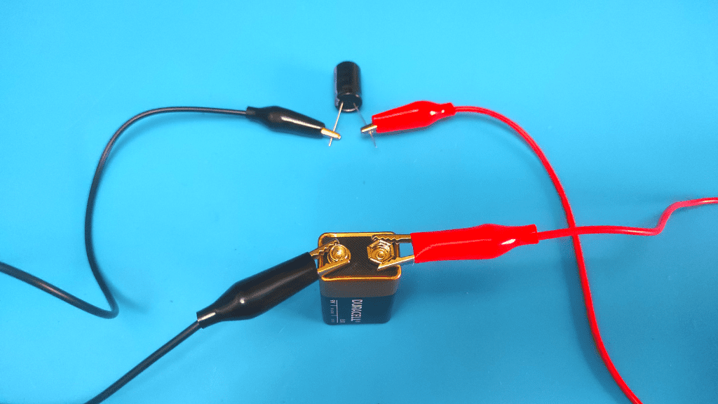 connect battery with jumper cables to capacitor pins